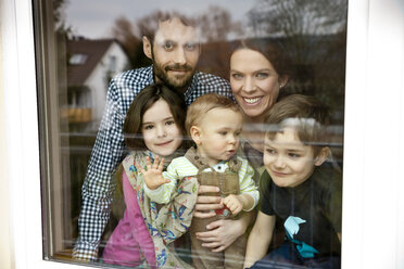 Glückliche fünfköpfige Familie schaut durch eine Fensterscheibe - MFF002974