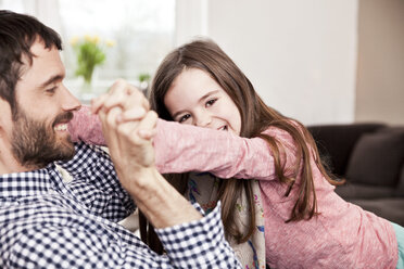 Daughter playfighting with her father on the couch - MFF002978