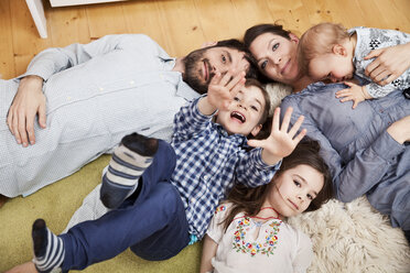 Family with three children lying on the floor at home looking at camera - MFF002992