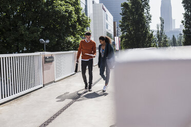 Young man and woman discussing document outdoors - UUF007487