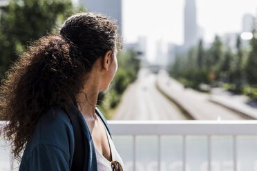 Young woman on bridge looking on street - UUF007488