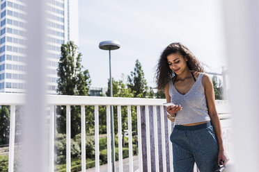 Junge Frau auf Brücke schaut auf Handy - UUF007502