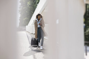 Young woman with luggage and cell phone on the move - UUF007511