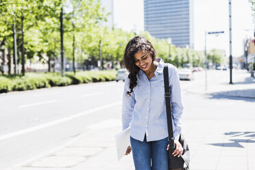 Smiling young woman on the move in the city - UUF007535