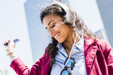 Happy young woman with headphones outdoors - UUF007545