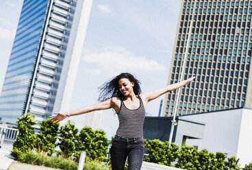Enthusiastic young woman with outstretched arms outdoors - UUF007560