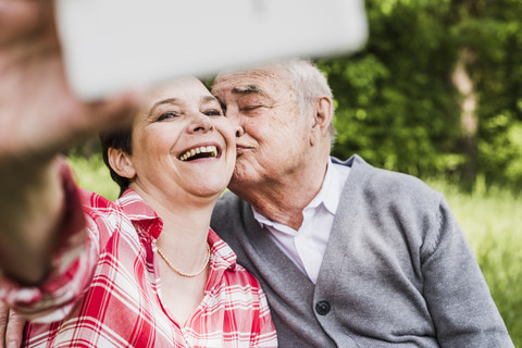 Frau nimmt Selfie mit ihrem alten Vater in der Natur, lizenzfreies Stockfoto