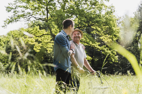 Glücklicher Großvater beim Spaziergang mit seinem Enkel in der Natur, lizenzfreies Stockfoto