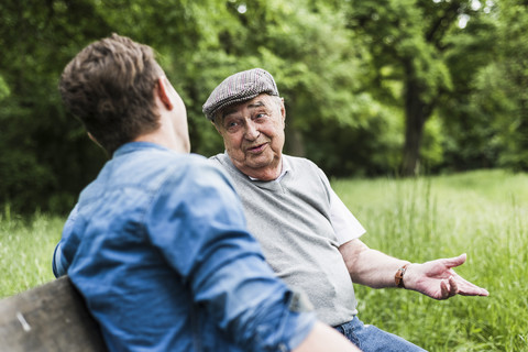 Porträt eines älteren Mannes, der auf einer Bank sitzt und mit seinem Enkel spricht, lizenzfreies Stockfoto