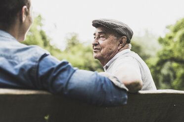 Portrait of senior man talking with his grandson on a bench - UUF007599