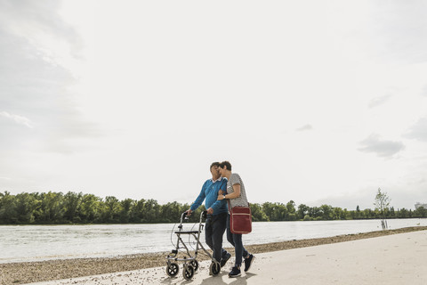 Älterer Mann geht mit Tochter am Flussufer spazieren, lizenzfreies Stockfoto