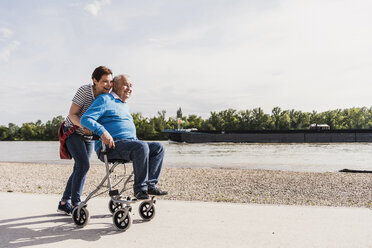 Woman pushing her old father sitting on wheeled walker - UUF007619