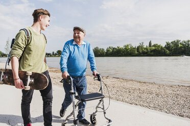 Grandfather and grandson strolling together at riverside - UUF007624