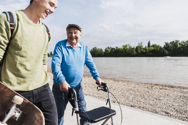 Grandfather and grandson strolling together at riverside - UUF007625