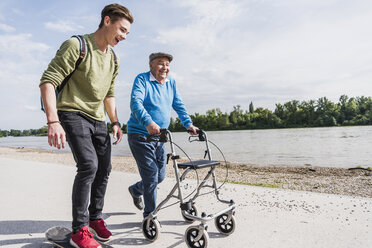 Grandfather and grandson strolling together at riverside - UUF007626