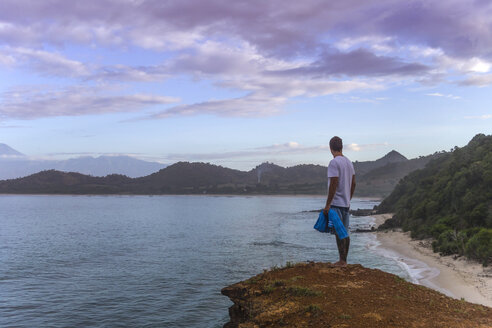 Indonesia, Sumbawa island, Young man standing on viewpoint - KNTF000297