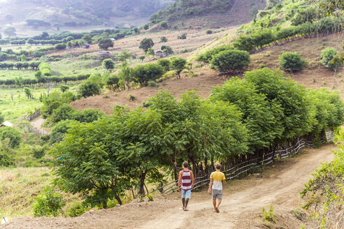 Indonesia, Sumbawa island, Two young men walking on a dirt road - KNTF000303