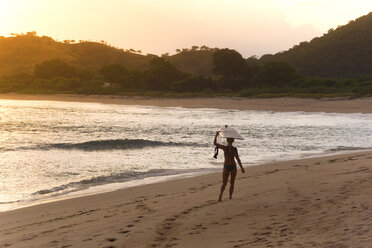 Indonesia, Sumbawa island, Surfer girl at the beach in the evening - KNTF000306