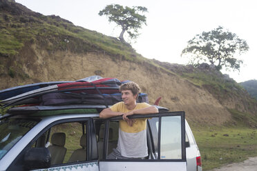 Indonesia, young surfer standing at his car - KNTF000309