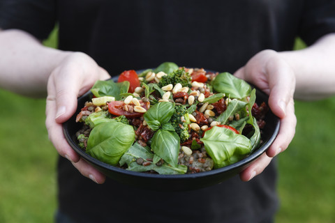 Hände halten Schüssel mit zubereitetem Reissalat, lizenzfreies Stockfoto