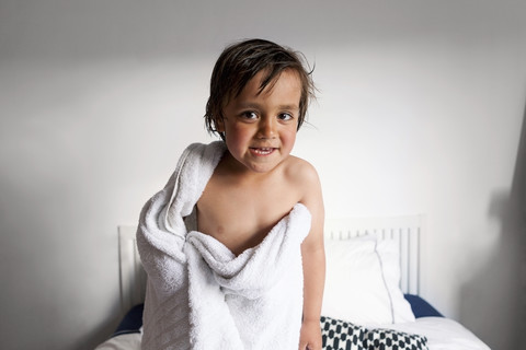 Porträt eines kleinen Jungen mit Duschtuch, der nach dem Baden lustige Gesichter zieht, lizenzfreies Stockfoto