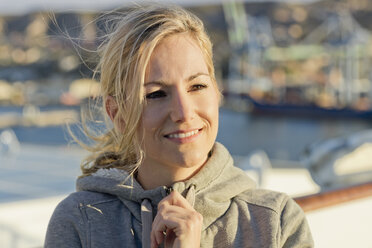 Portrait of smiling blond woman on deck at sunlight - ONBF000050