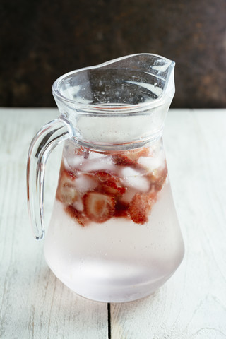 Karaffe mit Sprudelwasser, Eiswürfeln und Erdbeerscheiben, lizenzfreies Stockfoto