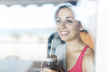 Smiling young woman holding mug with healthy drink - JRFF000740