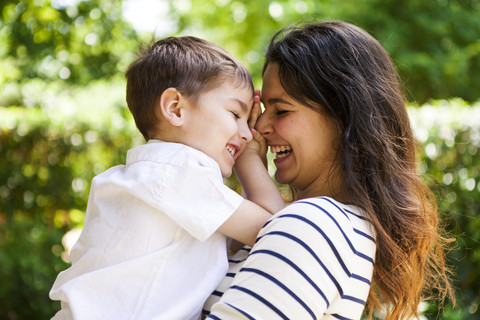 Glückliche Mutter und Sohn umarmen sich im Freien, lizenzfreies Stockfoto