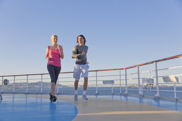 Junges Paar joggt auf dem Schiffsdeck eines Kreuzfahrtschiffs, Mittelmeer - ONBF000059