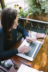 Junge Frau sitzt auf dem Balkon und benutzt einen Laptop - BOYF000370
