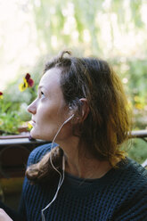 Junge Frau auf Balkon hört Musik mit Smartphone - BOYF000391