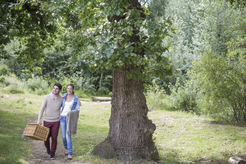 Junges Paar mit Picknickkorb beim Spaziergang in der Natur - ZEF008669