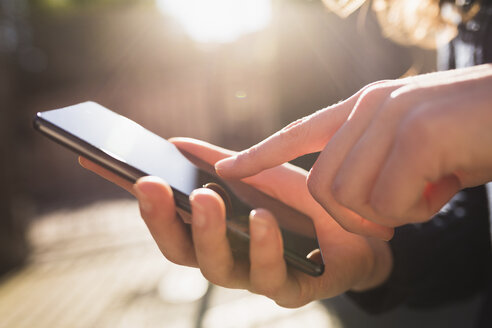 Der Finger einer Frau berührt das Display eines Smartphones - BOYF000405