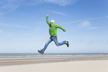 Enthusiastic mature man jumping on beach - GWF004740