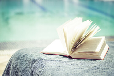 Aufgeschlagenes Buch auf dem Handtuch im Schwimmbad - CMF000469