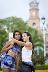 Mexiko, Puerto Vallarta, zwei junge Frauen machen ein Smartphone-Selfie in der Stadt - ABAF002039