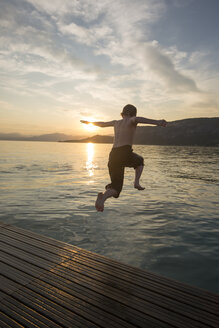 Italien, Venetien, Bardolino, Gardasee, Junge springt bei Sonnenuntergang ins Wasser - SARF002735