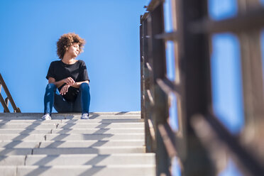 Frau sitzt auf einer Treppe im Sonnenlicht - SIPF000527