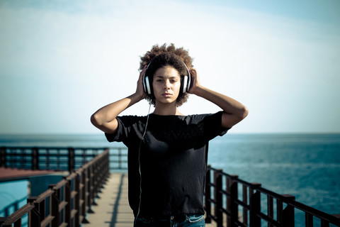 Portrait of serious woman with headphones on a jetty stock photo