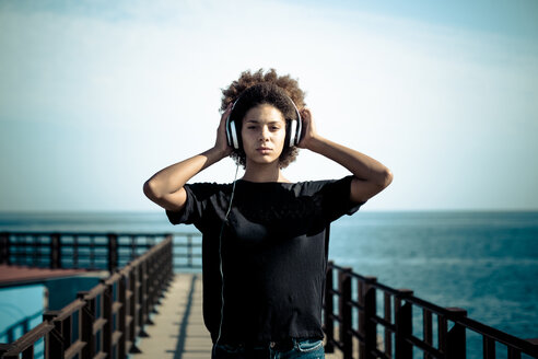Portrait of serious woman with headphones on a jetty - SIPF000528