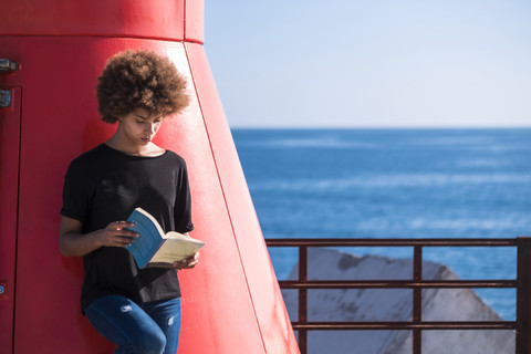 Junge Frau an Deck, die ein Buch liest, lizenzfreies Stockfoto