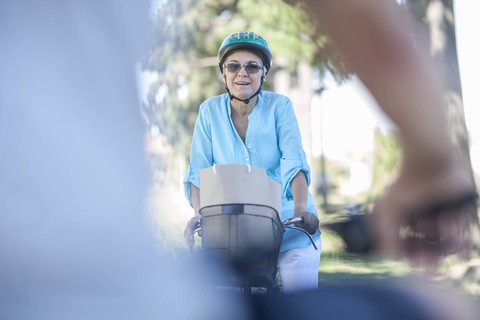 Lächelnde ältere Frau auf dem Fahrrad, lizenzfreies Stockfoto
