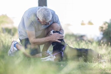 Senior man petting his dog outddors - ZEF008701