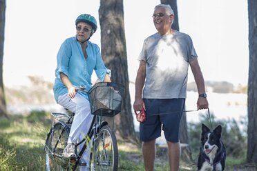 Elderly couple with dog and bicycle in forest - ZEF008703