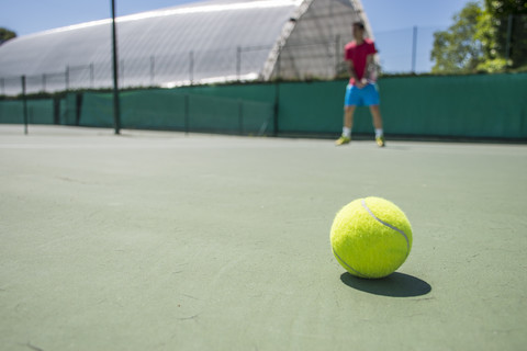 Tennisball mit unscharfem Tennisspieler im Hintergrund, lizenzfreies Stockfoto