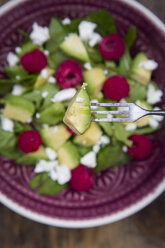 Avocado auf Gabel mit Avocado-Himbeer-Salat im Hintergrund - LVF004941