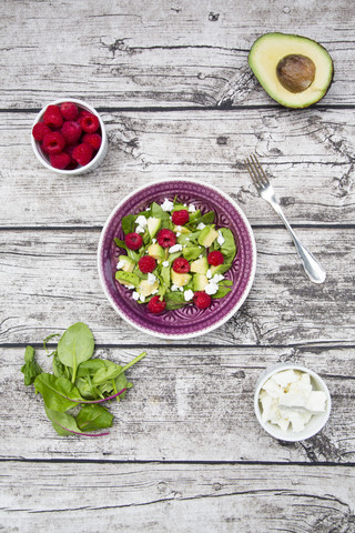 Schüssel mit Avocado-Himbeer-Salat mit Feta und Schalen mit Zutaten, lizenzfreies Stockfoto