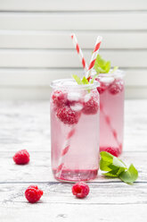 Raspberry champagne in glasses, drinking straw, mint and raspberries - LVF004951