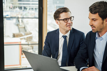 Two businessmen with laptop talking in office - CHAF001766